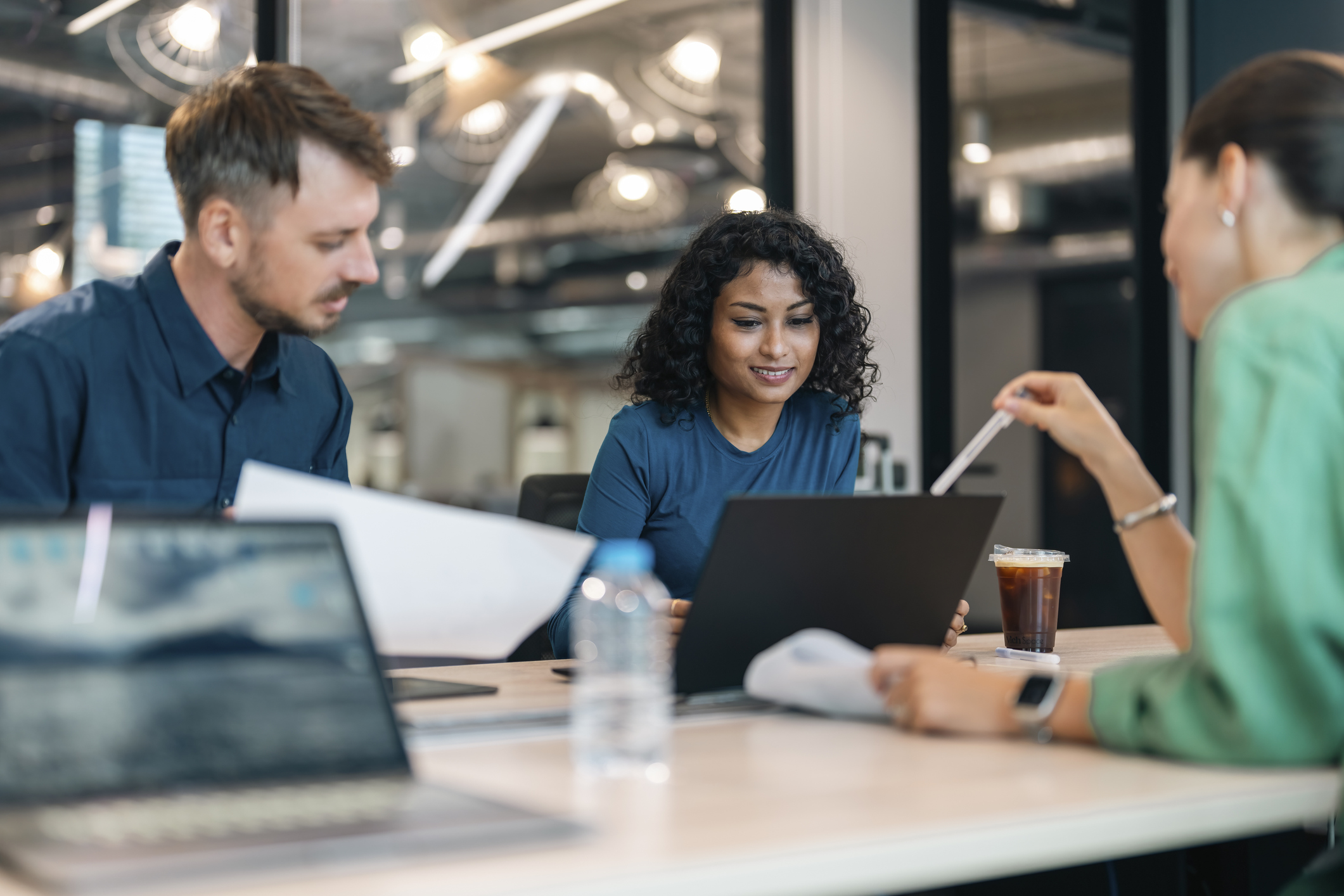 three colleagues working together over a laptop at a table in an office