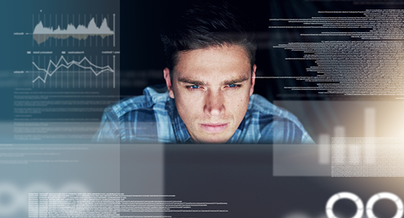 man looking intently at a computer surrounded by coding and graphs